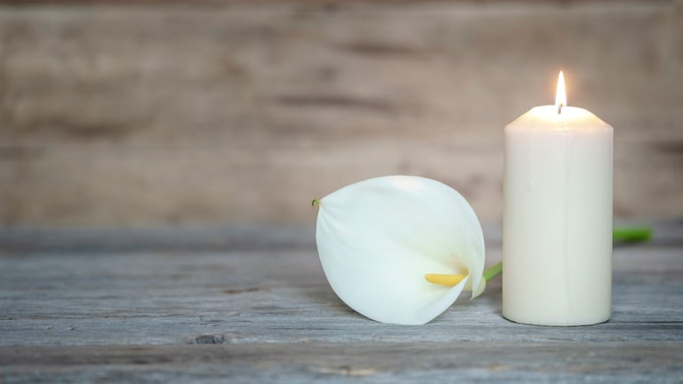 Flor de lis y vela encendida como símbolo de recuerdo
