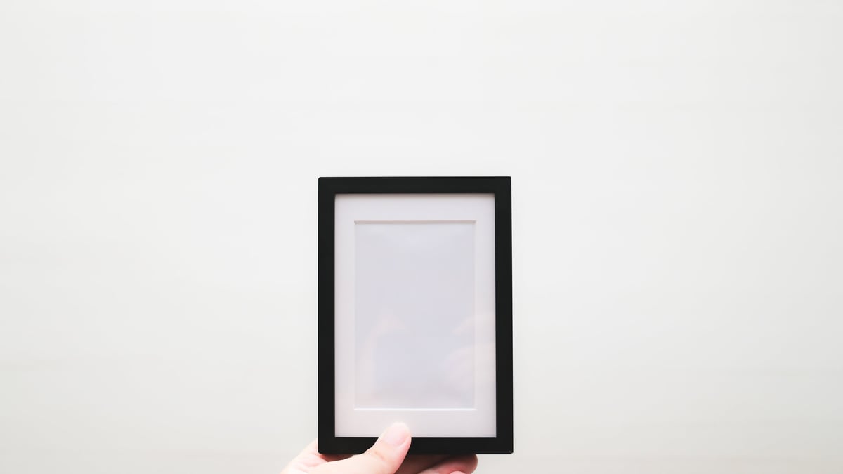 A tourist holds a white photo frame with a blank white background, perfect as a digital mockup for ads or other applications.